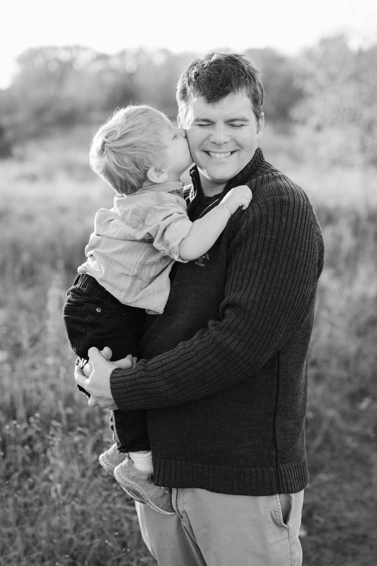 little boy kissing father on the cheek. Black and white image. 
