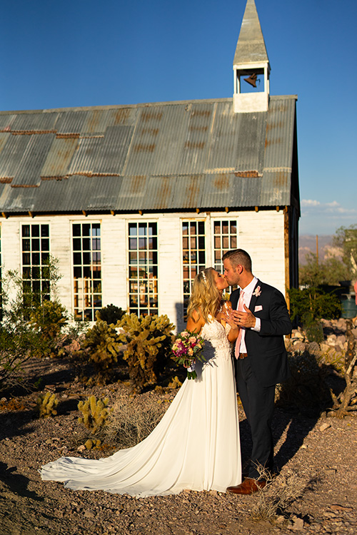 a bride and groom kissing in front of the wedding chapel