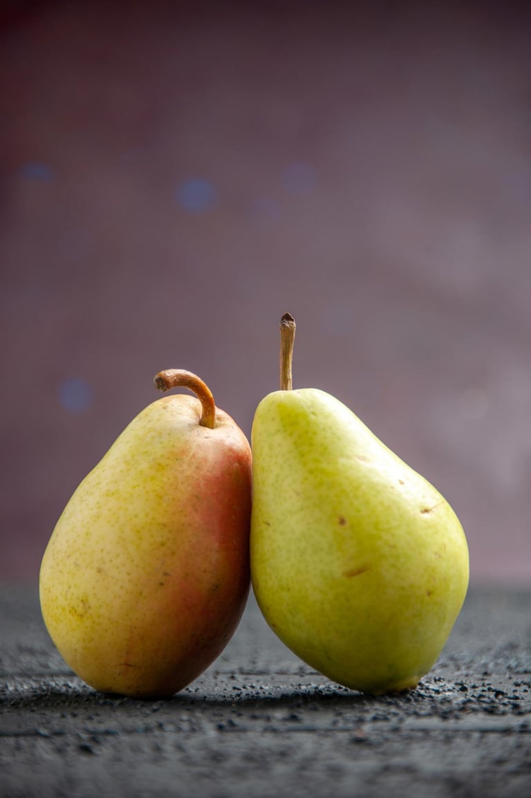 Two fresh organic pears standing on a dark textured surface with a purple background.