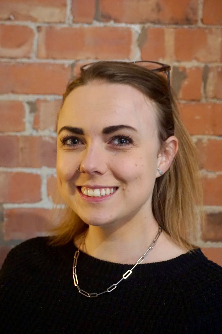 Coach Moll - a woman in her thirties with glasses and a black sweater