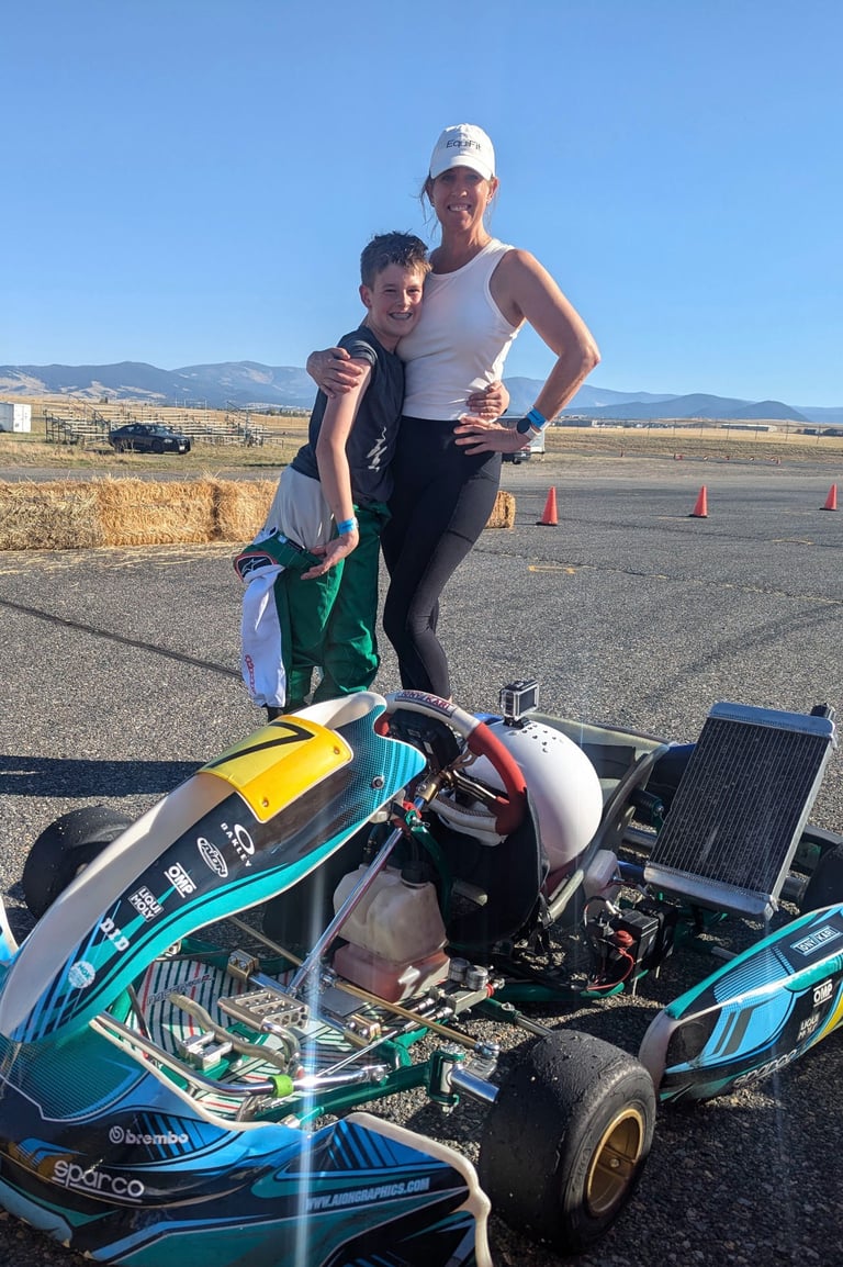 a woman and a boy are standing next to a race car