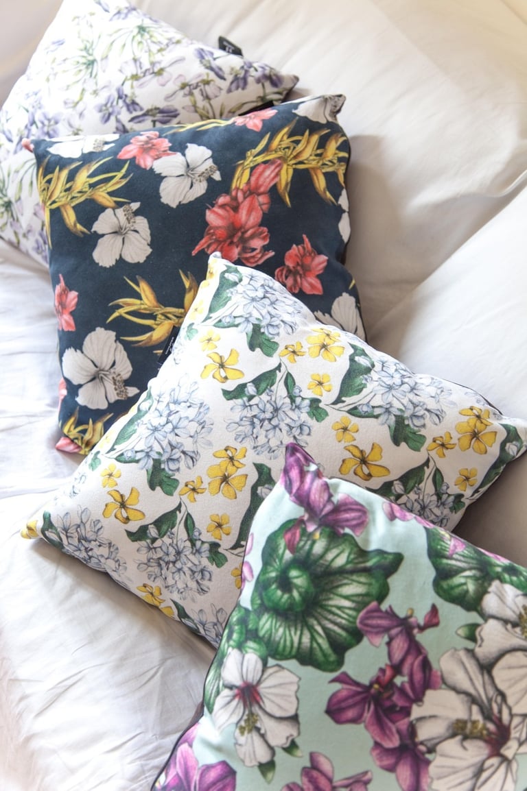 Four Pillows with multicolor hand-drawn floral patterns on a white couch