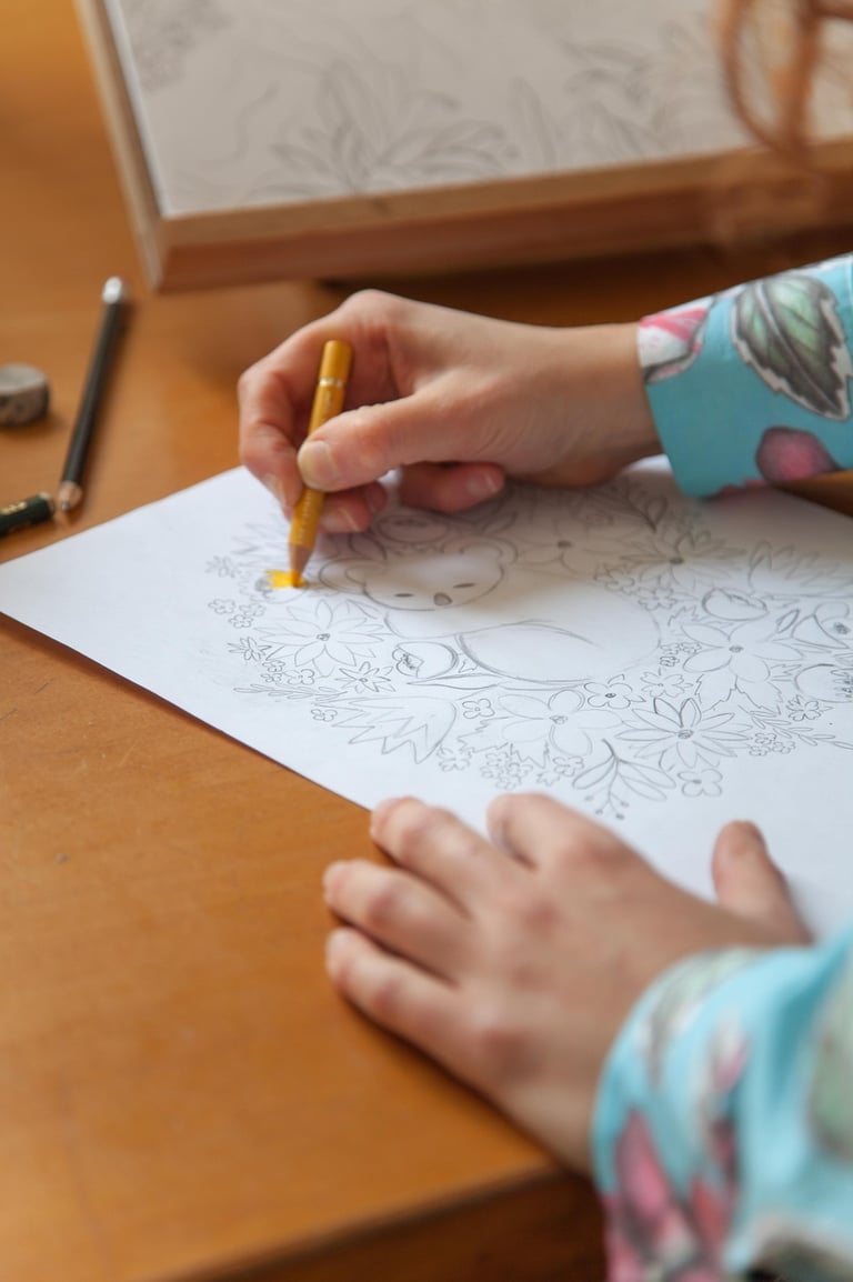 Hands making a koala illustration with colored pencils