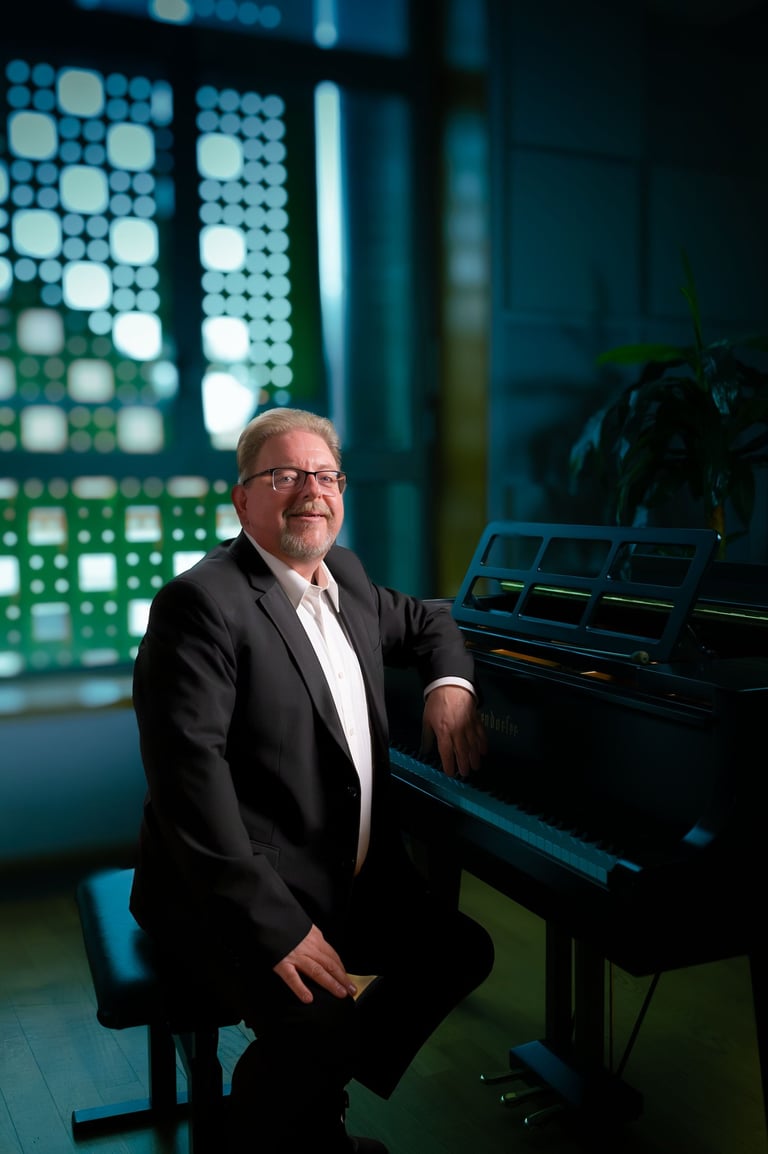 Robert in a suit and tie is sitting at a piano