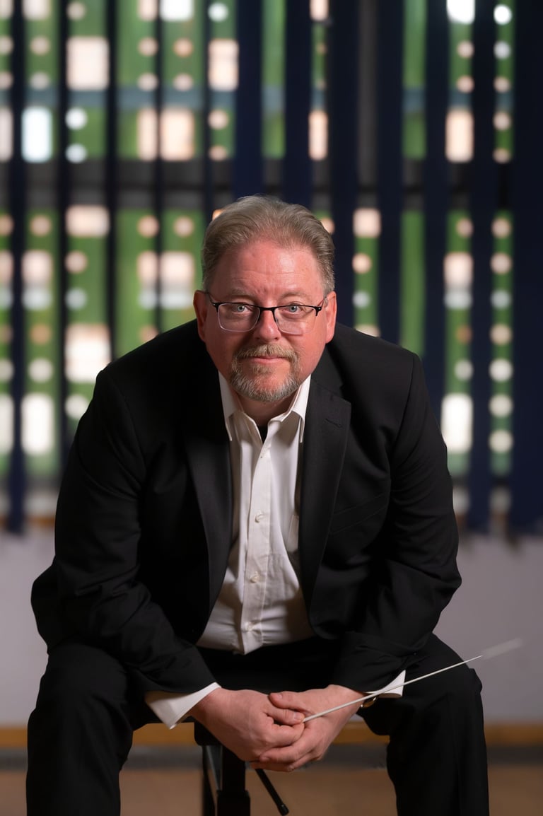 Robert in a suit and tie is sitting on a chair