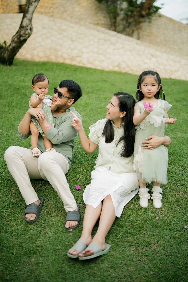 Father sitting with his children on a tropical resort lawn during a family photography session in Bali.