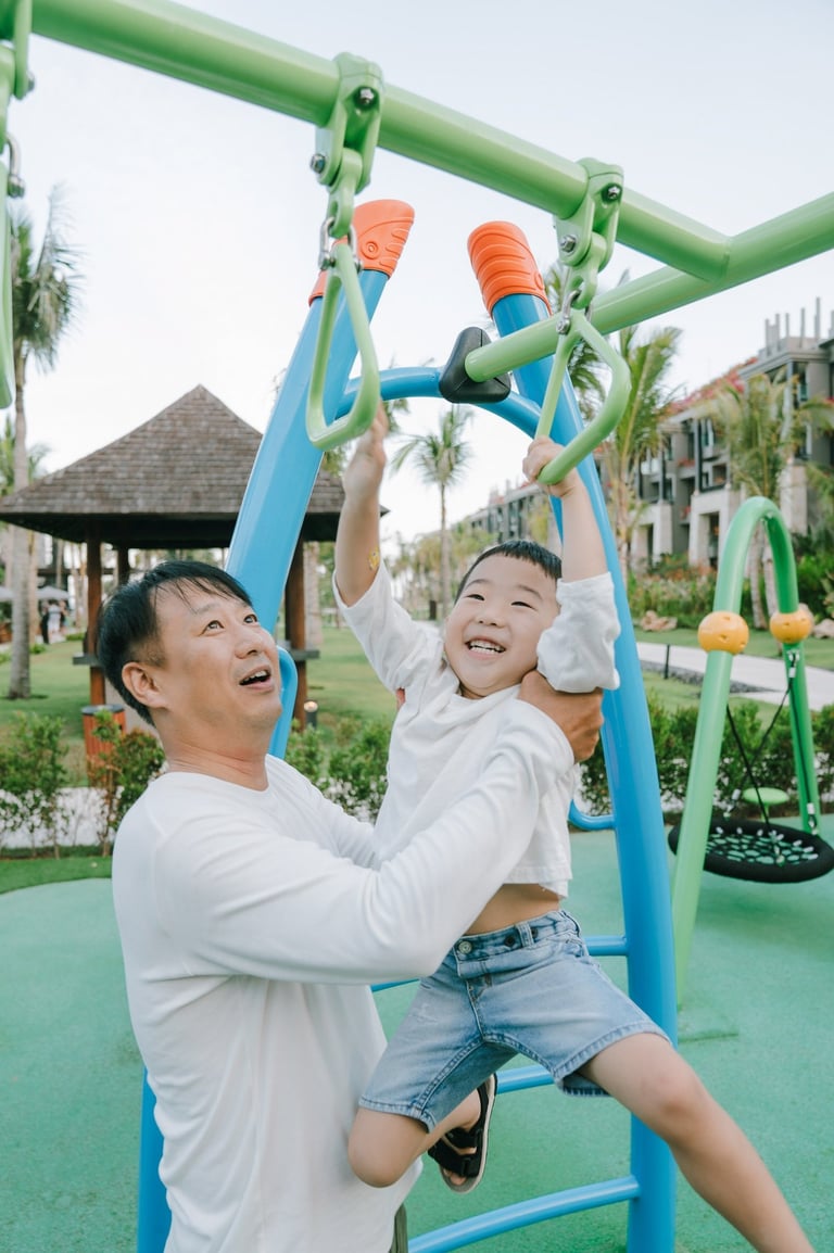 Family photography session at The Apurva Kempinski Bali playground area featuring joyful parent and child interaction.