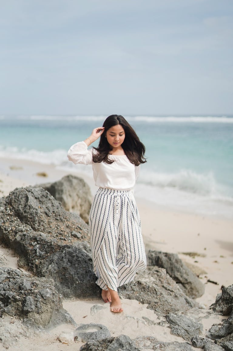 Young girl standing on rocks by the beach at Karma Kandara Bali  