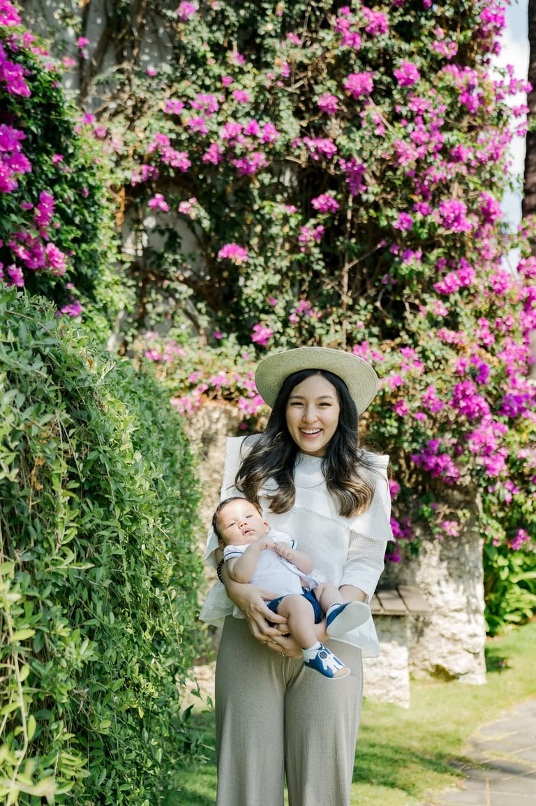 Mother carrying her baby in the tropical gardens of Samabe Bali Suites & Villas in Nusa Dua.