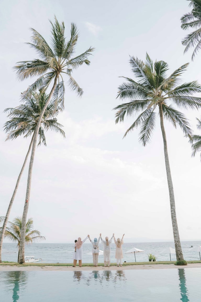 Friends standing near palm trees during photoshoot at Candi Beach Resort Karangasem Bali