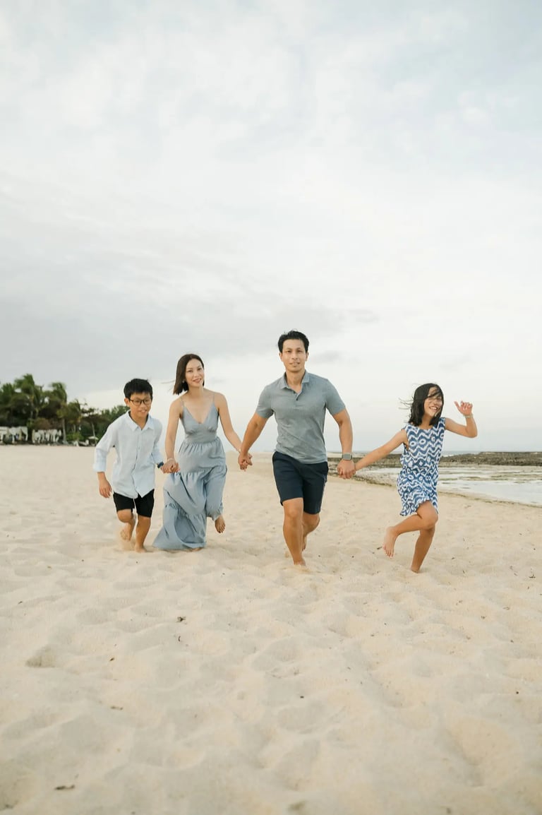 Family running together along the beach during a luxury family photography session at The Ritz-Carlton Bali.