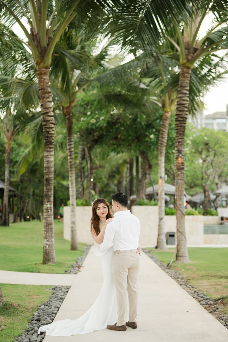 Couple standing together on a tropical garden pathway during a prewedding photoshoot at Apurva Kempinski Bali