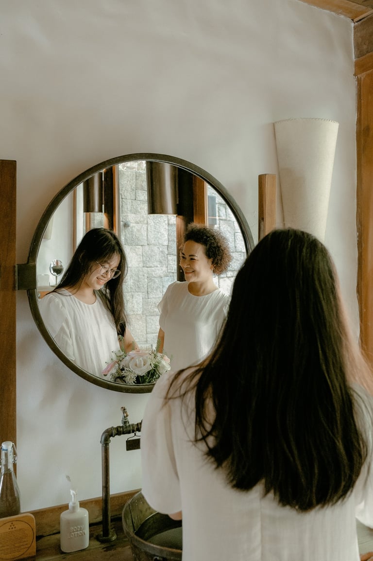 a woman in a white shirt is looking at her reflection in a mirror