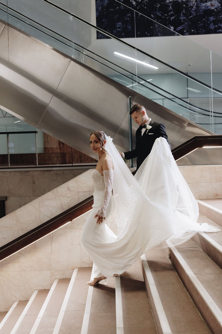 a bride and groom walking down a flight of stairs