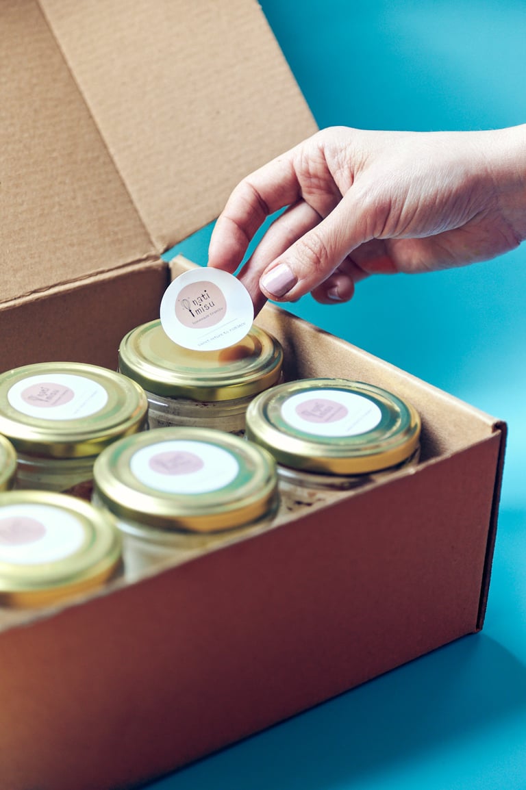 Hand putting on a sticker on tiramisu jars.
