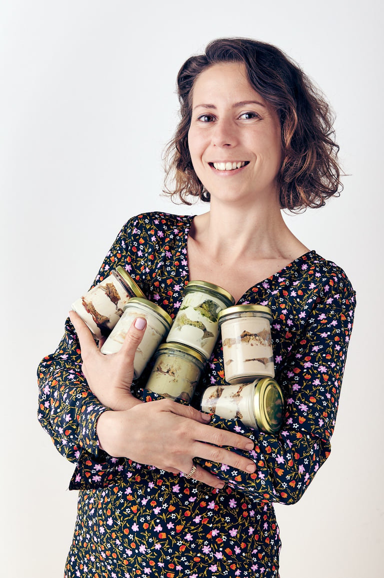 Smiling woman holding jars of tiramisu.