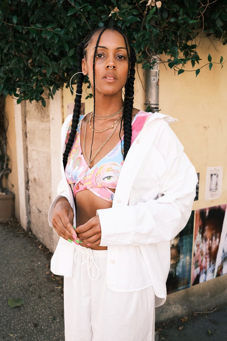 portrait d'une femme noire avec brassière colorée et pantalon ample blanc