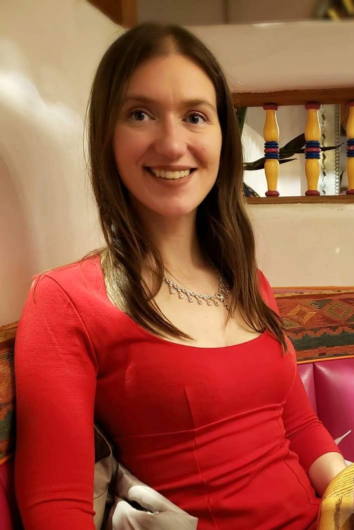 Stephanie Marie, Super Wellness Woman, wearing a red dress and a necklace, smiling a the camera.
