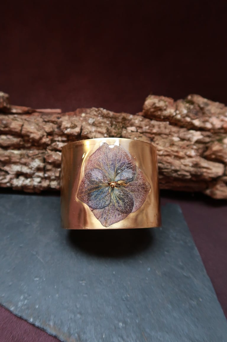 les bracelets styx manchettes dorés aspect magique, irréel, ornés de fleurs et de plumes