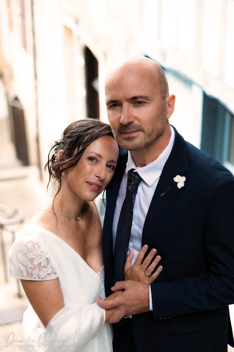 couple de mariés qui se prennent dans les bras en regardant l'objectif