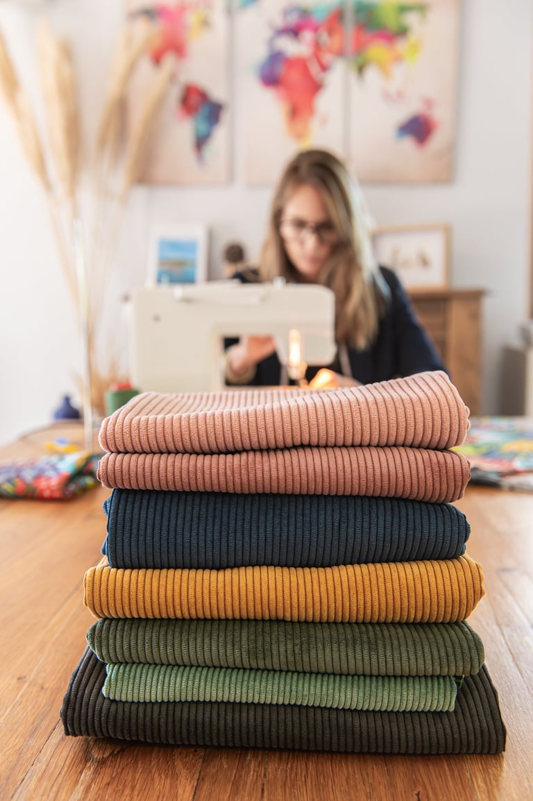 séance photo professionnelle d'une couturière en train de coudre avec ses tissus devant