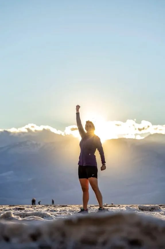 a woman standing on top of a slope feeling victory with life from bible answers she got