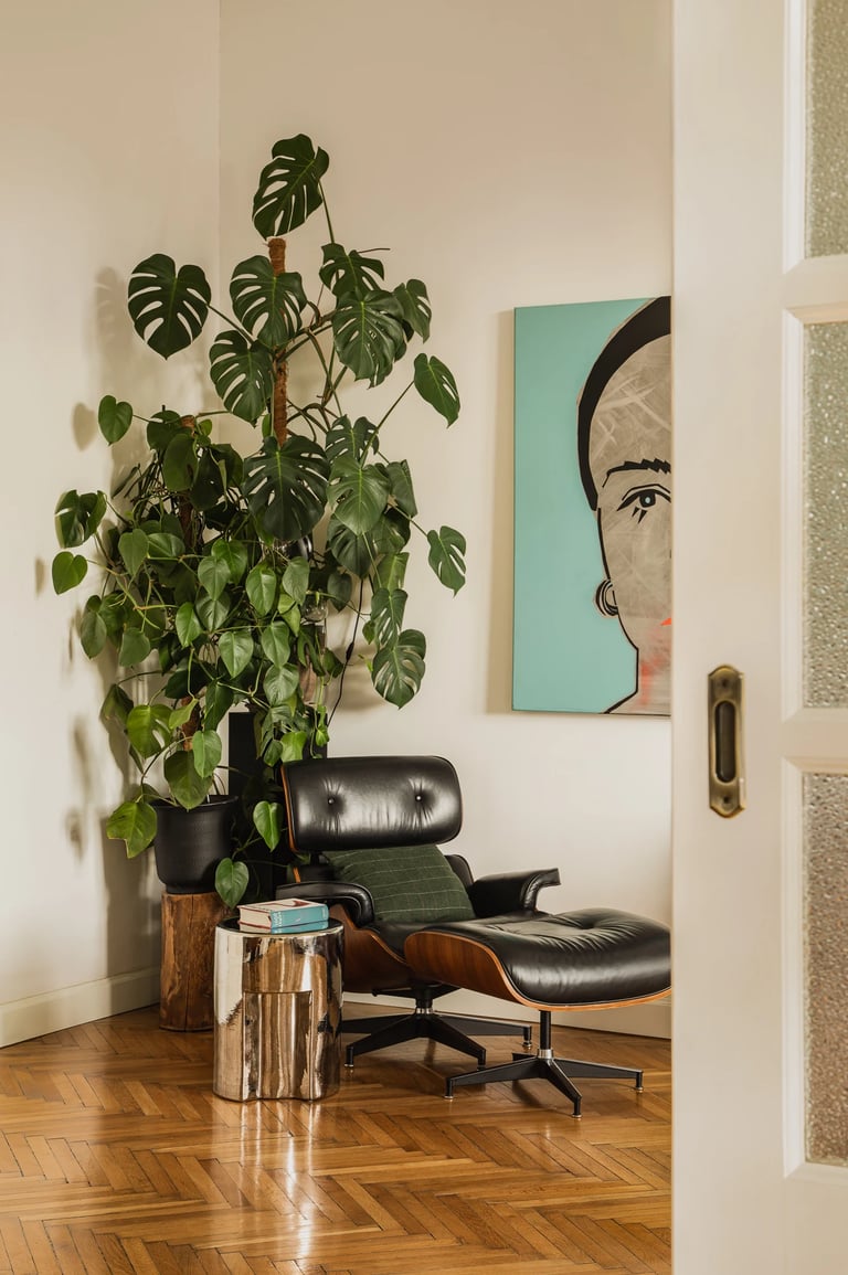Kultowy fotel Eames Lounge Chair, duża monstera i obraz.