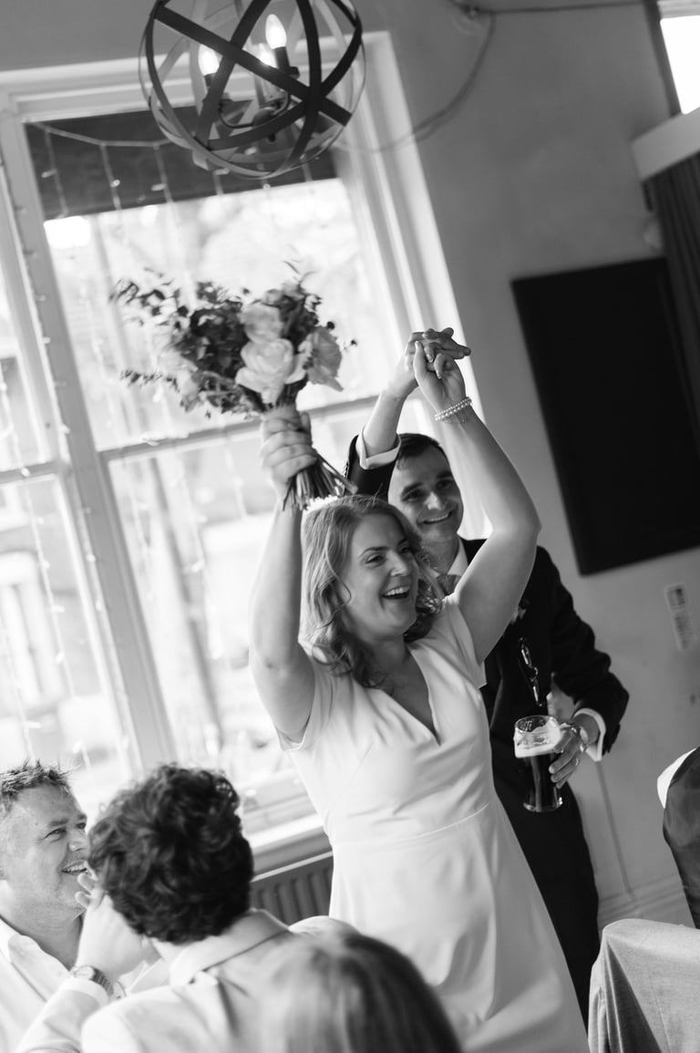 bride and groom raising their hands and smiling 