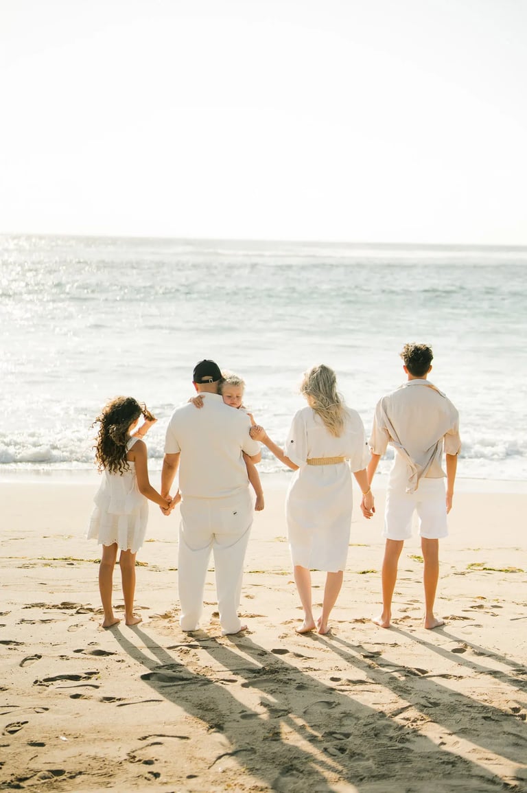 Family seen from behind walking toward the ocean during a family photography session at Ayodya Resort Bali
