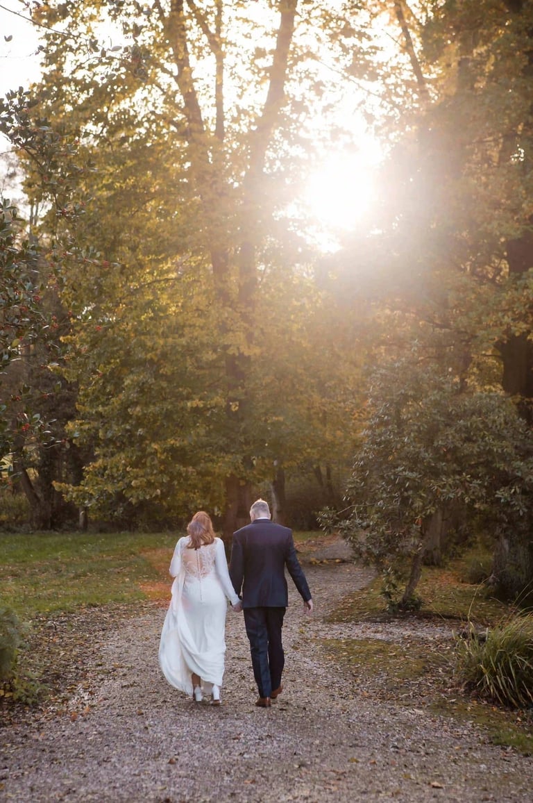 Bride and groom walk towards a sunset on their wedding day