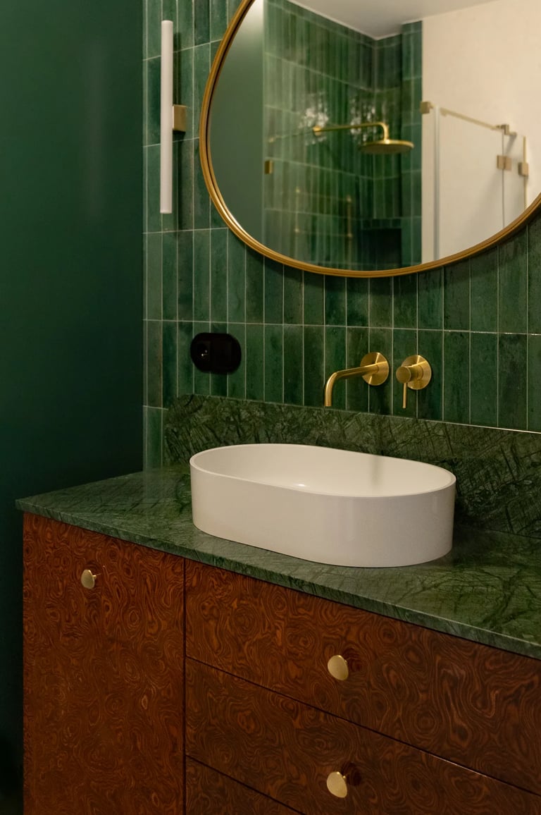 Kadr na armaturę: złota bateria i zielony kamień w łazience.