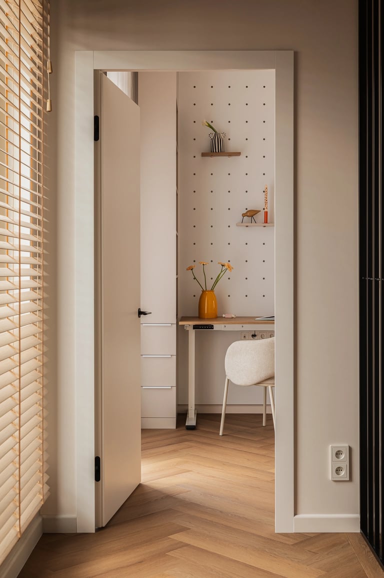 Widok z korytarza na pokój z biurkiem, drewniane żaluzje w oknie.