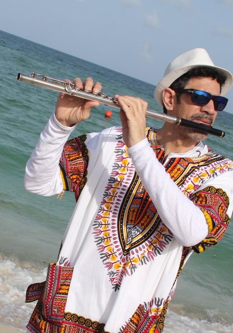 Maestro Bobby Ramirez wearing a Djembe shirt playing flute in Maimi Beach