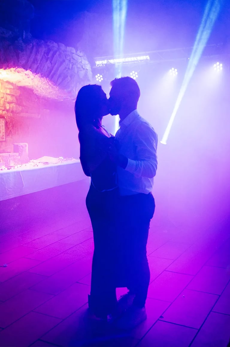 Danse d'un couple sous lumières colorées et ambiance festive en soirée de mariage.