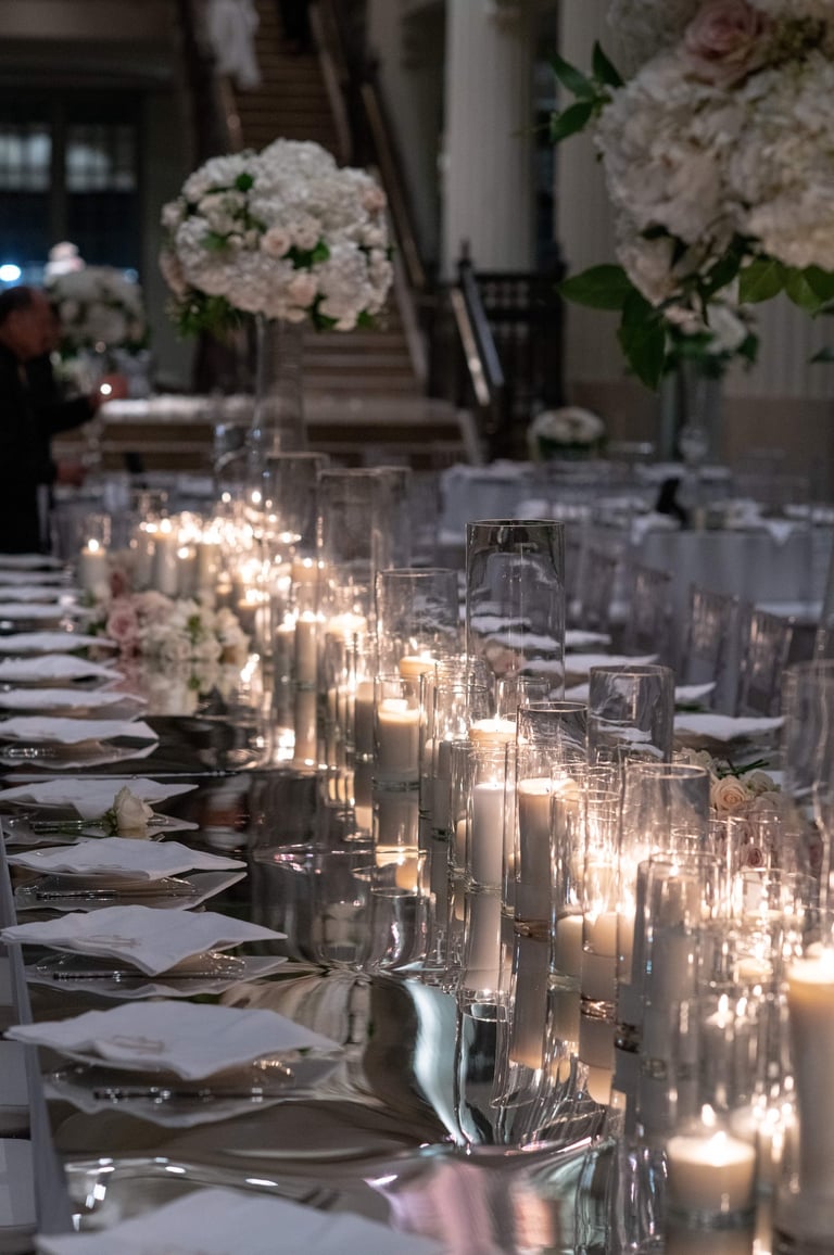 a long mirrored wedding reception table with candles and candles on it