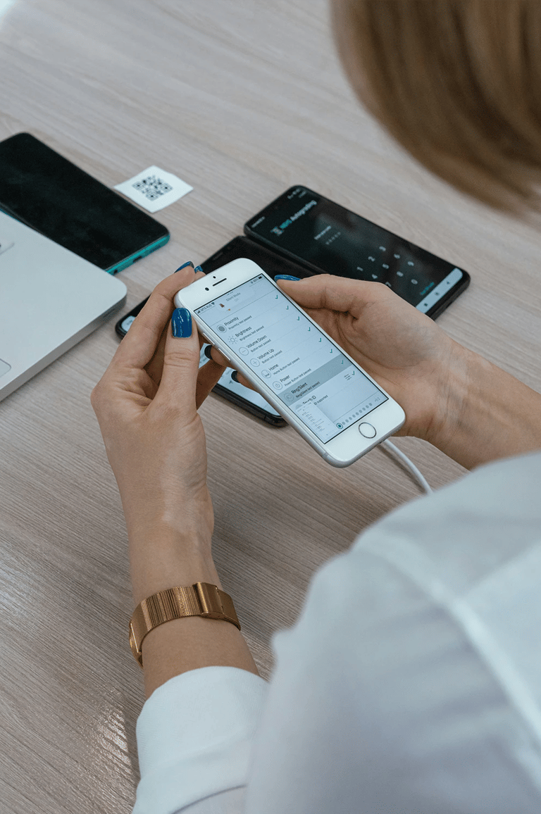 Woman at desk in Cedar Rapids setting up iPhone with other phones, laptop, and QR code for tech help.