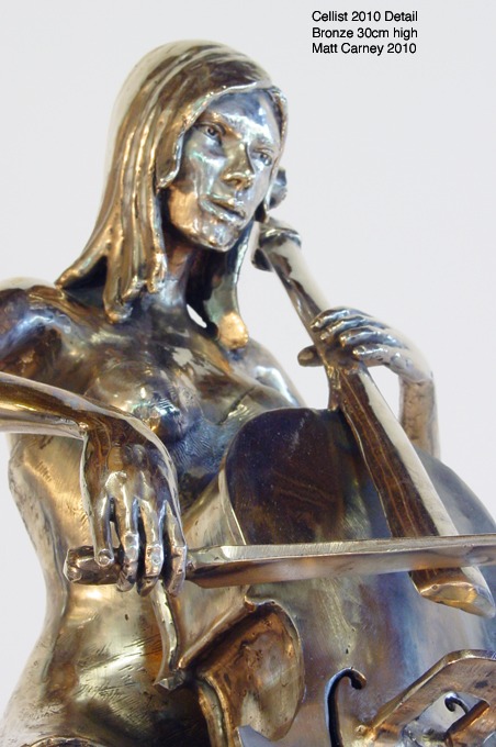 a bronze sculpture of a woman playing a cello