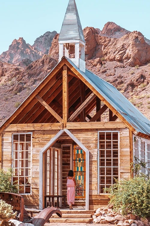 a woman in a pink dress standing in front of a church