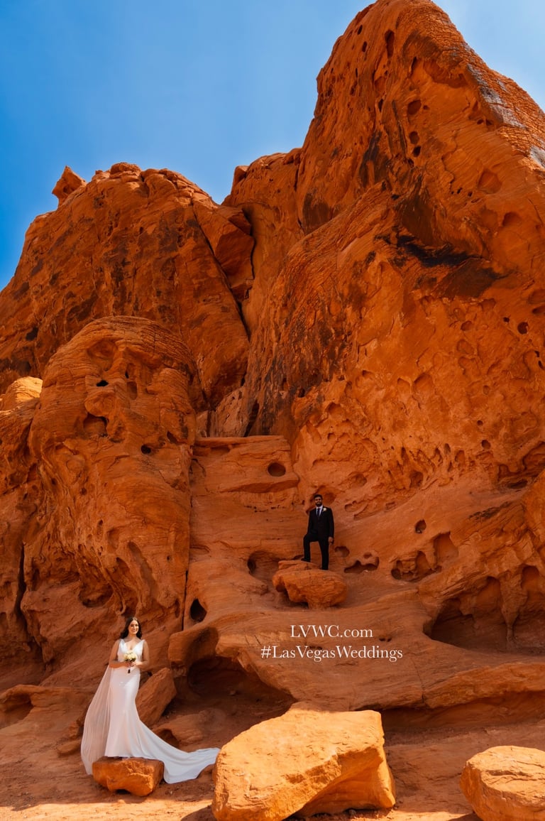 Bride and groom posing in front of towering red sandstone rock formations for a Las Vegas desert wedding.