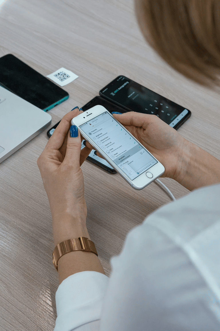 Woman at desk in Cedar Rapids setting up iPhone with other phones, laptop, and QR code for tech help.
