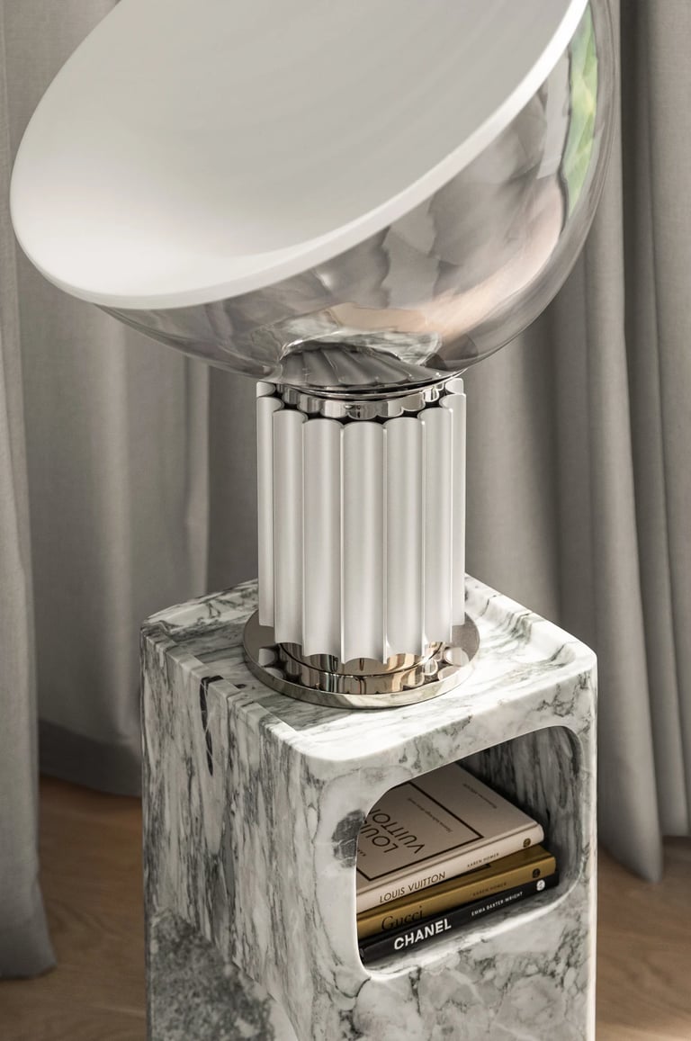 Luksusowy detal wnętrza: designerska lampa na marmurowym stoliku pomocniczym z książkami.