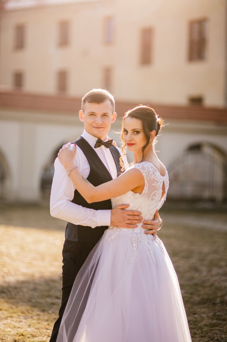 Jaunieji žvelgia į kamerą, jaunikis apkabinęs jaunąją