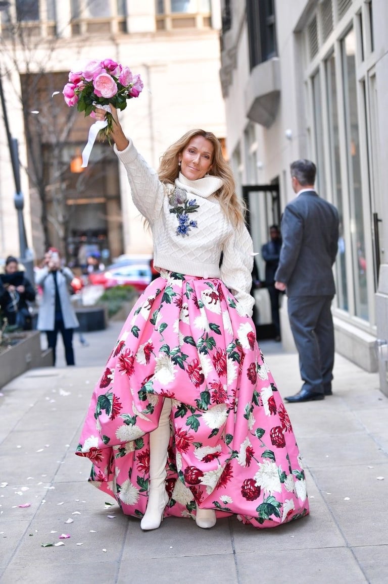 a woman in a pink dress and white boots is holding a bouquet