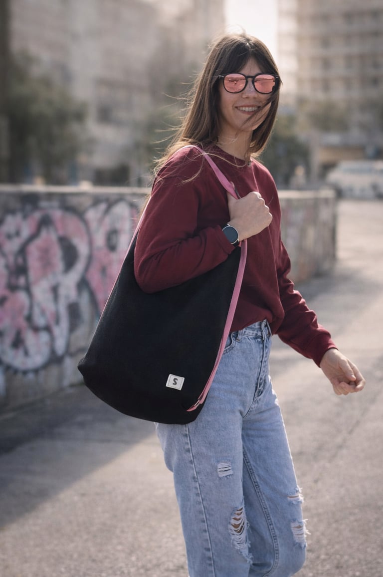 Bolso mochila negro artesanal de Sen Studio Atelier con correa rosa, llevado por mujer