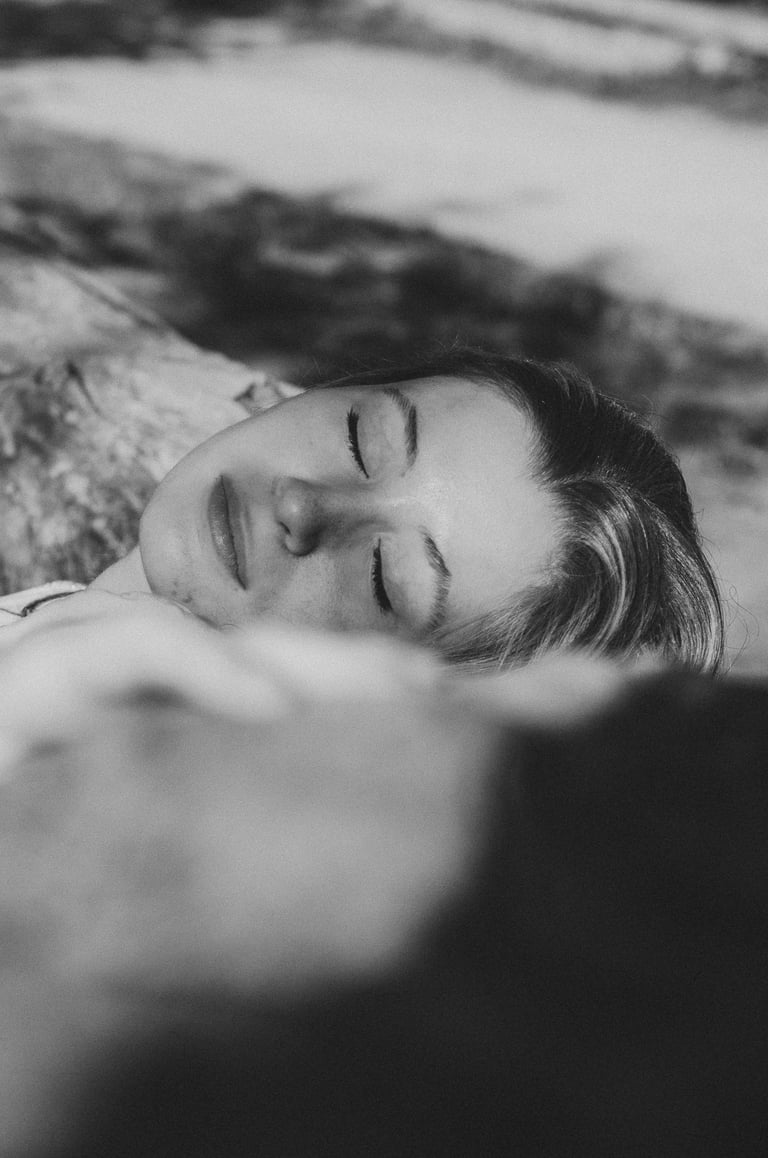 portrait féminin en noir et blanc yeux fermé allongé sur un tronc d'arbre