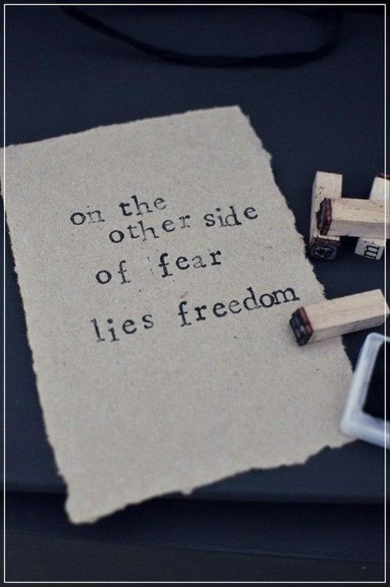 Inspirational quote stamped on paper reading on the other side of fear lies freedom.