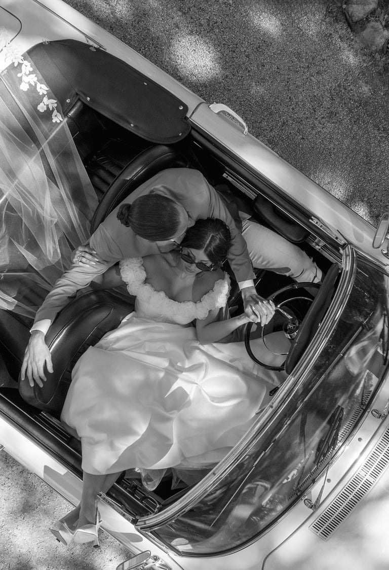 Photo aérienne de jeunes mariés dans une voiture décapotable vintage lors d'un mariage élégant