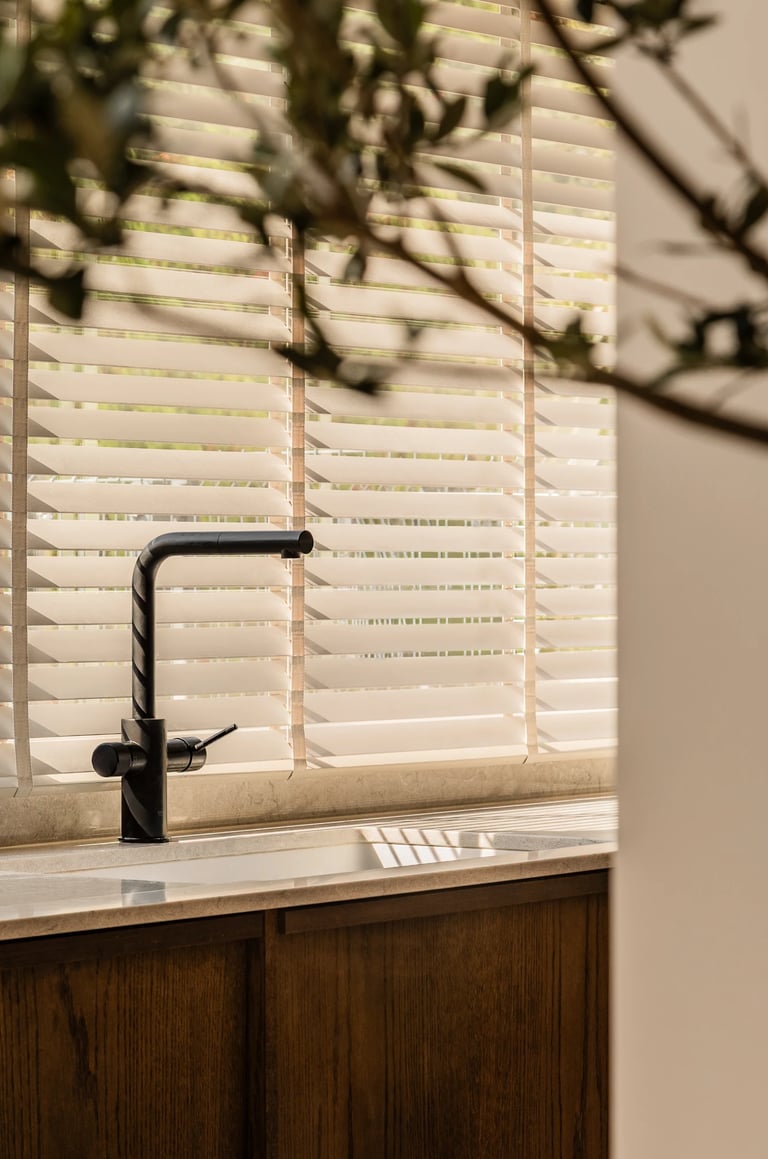 Kadr na strefę zmywania: czarna armatura i gra cieni z żaluzji.