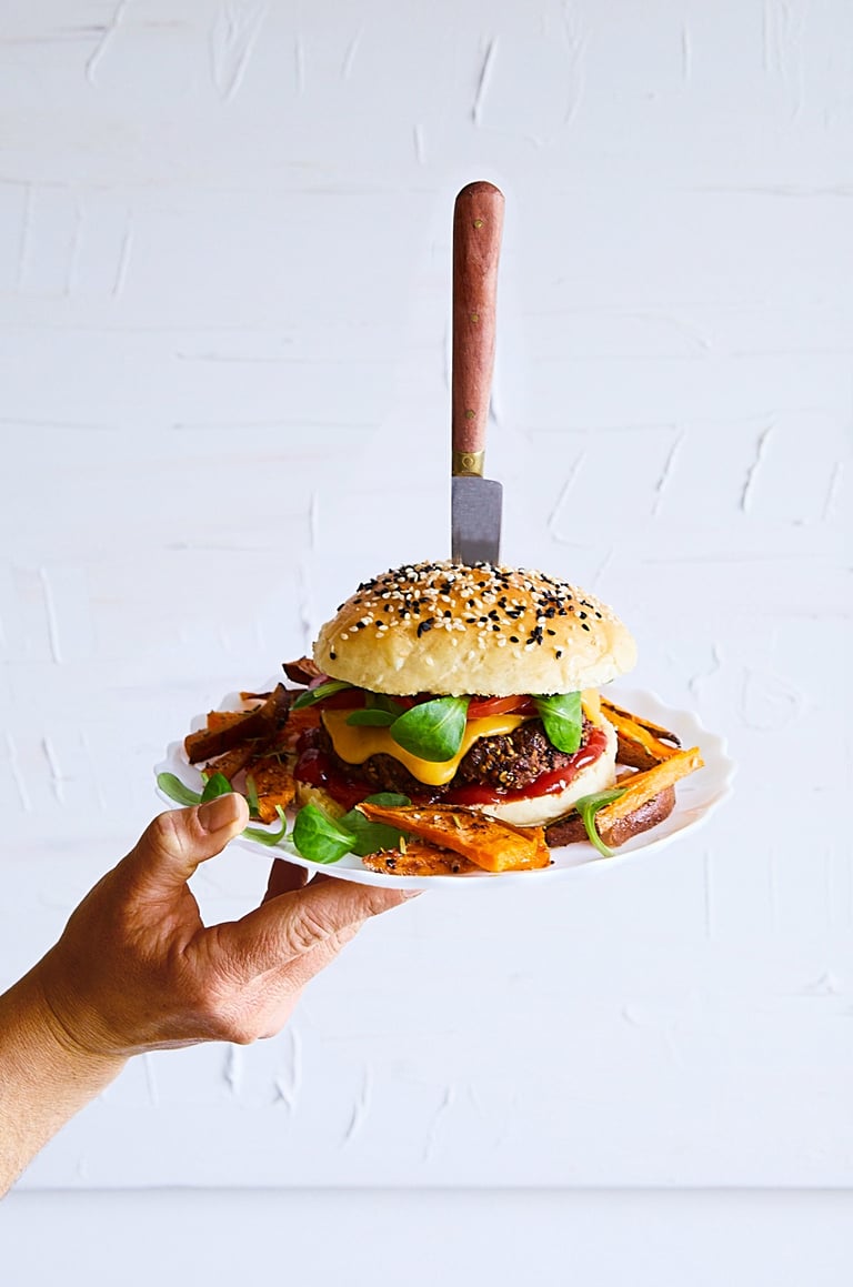 a person holding a plate with a hamburger burger on it