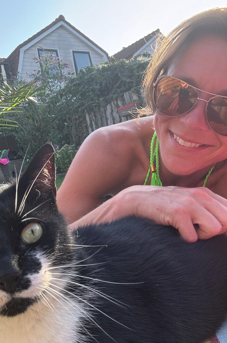 lachende vrouw met zonnebril met die een zwart witte kat aait